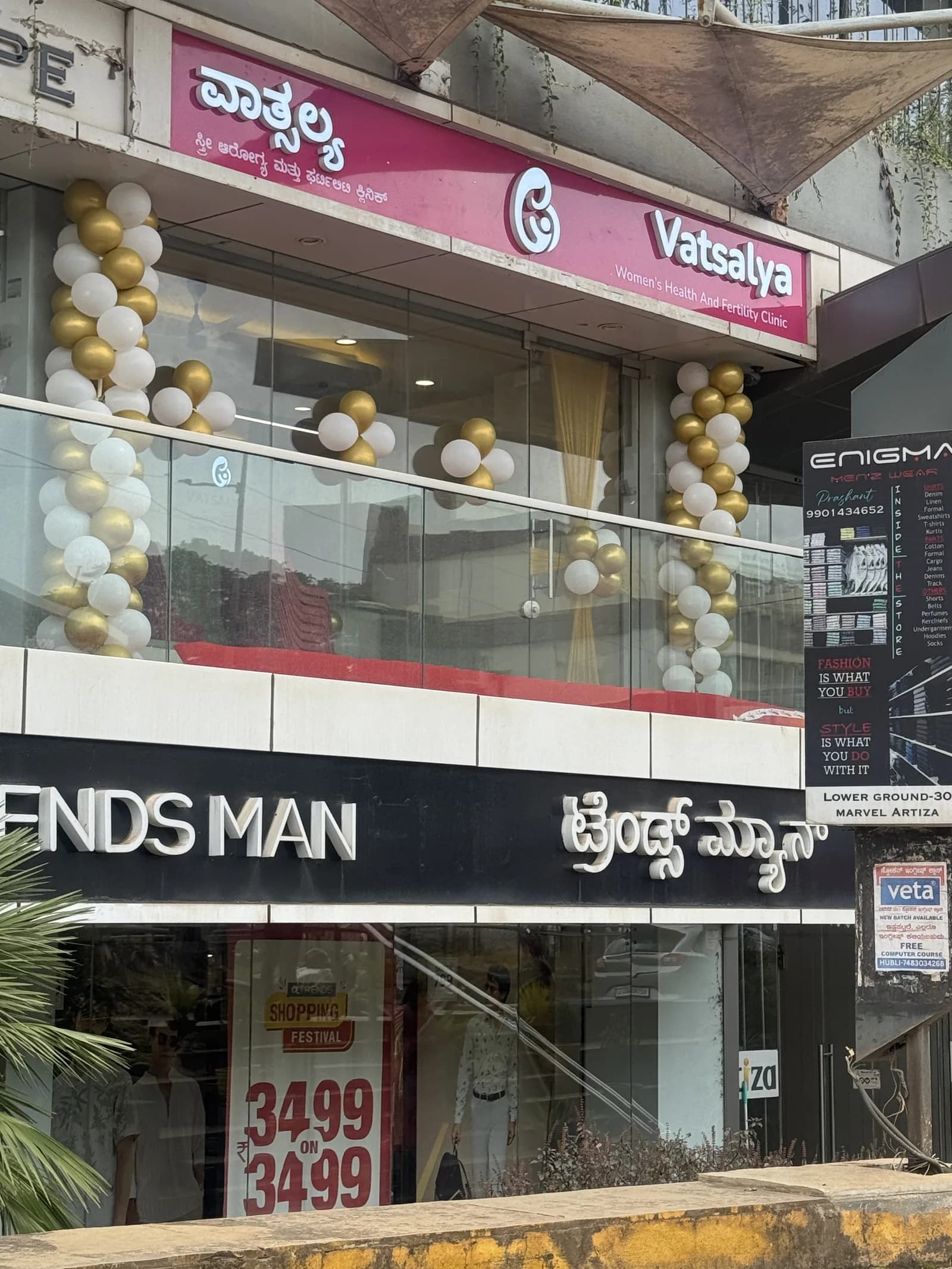 The Vatsalya clinic front by day: the magenta signboard in Kannada and English above the glass front, with the Trends Man store below